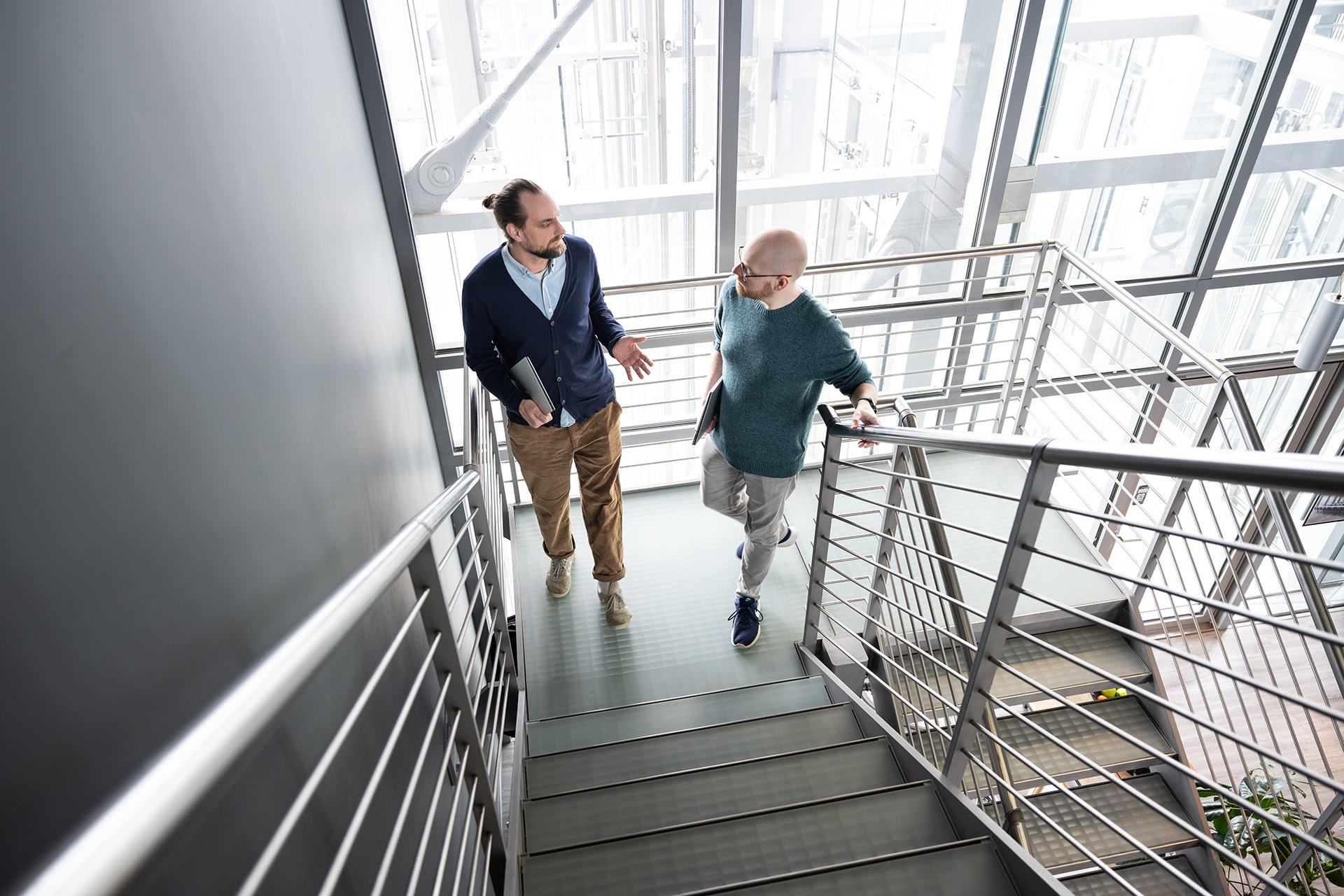 Two Cloudfalke colleagues having a discussion while walking up a modern office staircase