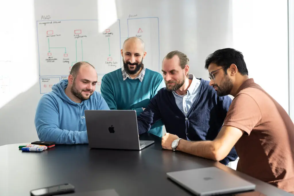 Cloudfalke IT consultants collaborating around a laptop during a strategy session